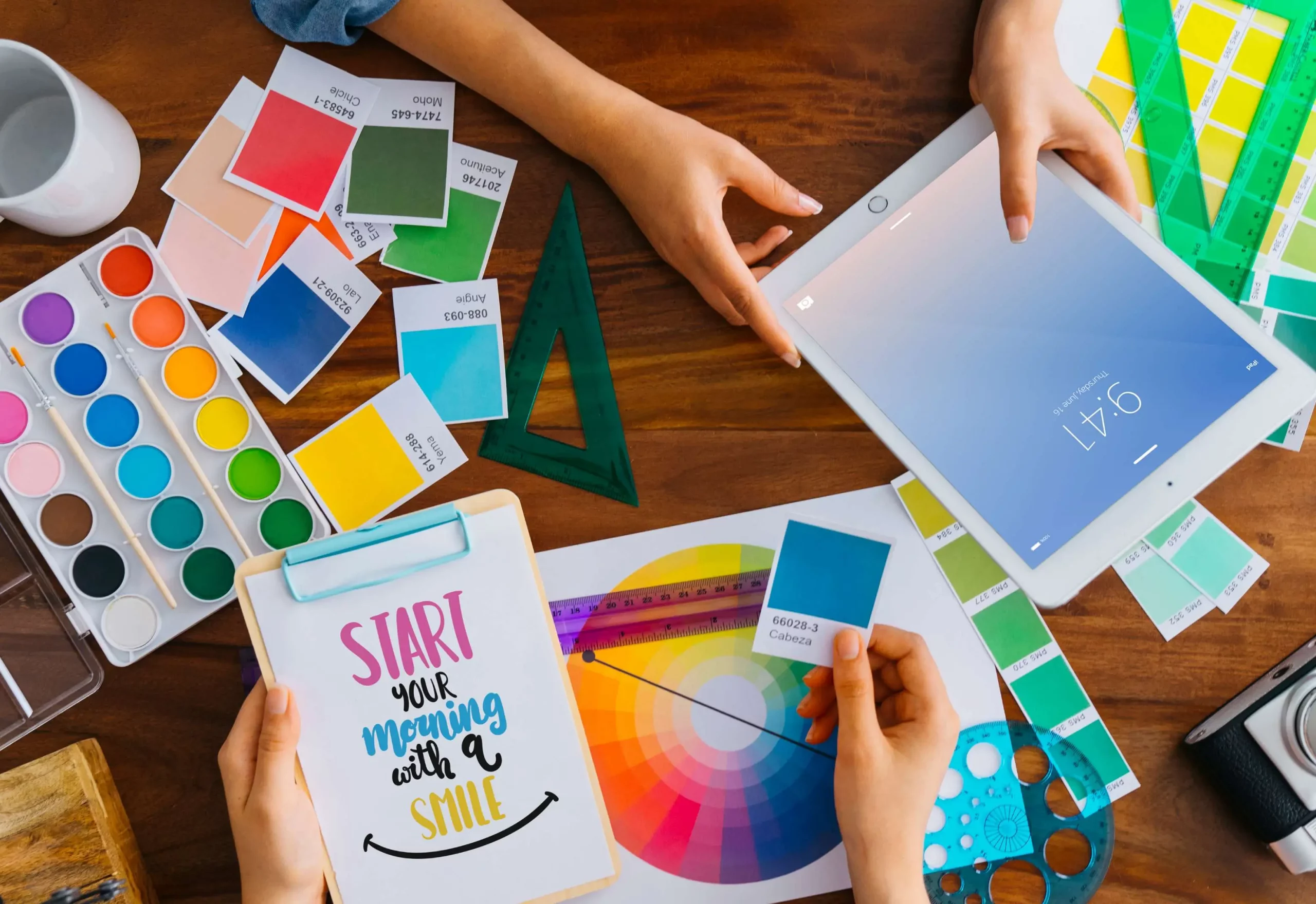 a group of hands holding a tablet and a paper with different colors